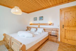Schlafzimmer mit einem Bett mit weißer Bettwäsche und einer Holzdecke in der Unterkunft Appartements Spitzegel in Hermagor