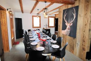 a long table with black chairs and a deer painting on the wall at Slope-Side Chalet w/Jacuzzi, Home Cinema, for 16 Guests in Montgenèvre
