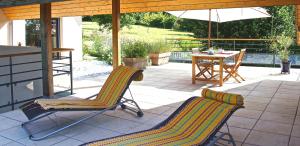 un patio con 2 sillas, una mesa y una sombrilla en Chambre d'hôtes La Dentalie en Rouffignac Saint-Cernin