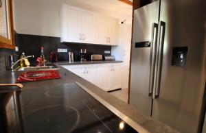 a kitchen with white cabinets and a stainless steel refrigerator at Slope-Side Chalet w/Jacuzzi, Home Cinema, for 16 Guests in Montgenèvre