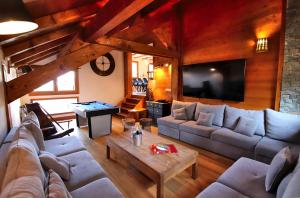 モンジェネヴルにあるSlope-Side Chalet w/Jacuzzi, Home Cinema, for 16 Guestsのソファとテレビのあるリビングルーム