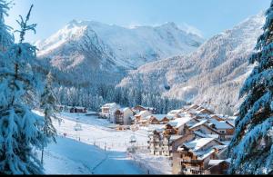 uma aldeia coberta de neve com montanhas ao fundo em Appartement les orres 1800 pied des pistes em Les Orres
