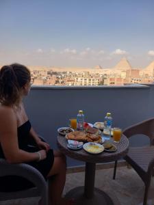 a woman sitting at a table with food and drinks at pyramids stone Top in Cairo