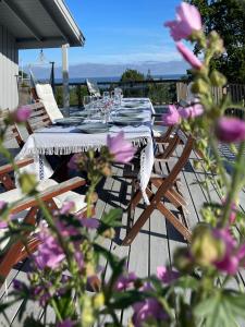 a table and chairs on a deck with purple flowers at Idyllic Cabin in Lillesand fantastic ocean view in Lillesand