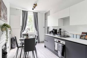 a kitchen with white cabinets and a table with chairs at Lovely apartment - Great Portland Street - LONDON ZOO - CENTRAL LOCATED in London