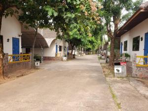 an empty street next to a building with trees at Phontong Garden Resort in Kalasin