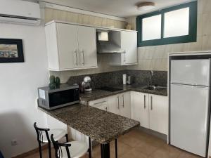 a kitchen with white cabinets and a counter with a microwave at Playa Ingles central cozy apartment in Maspalomas