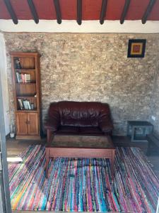 a brown leather couch sitting in a room with a rug at La Casita de Campo in Córdoba