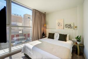 ein Schlafzimmer mit einem weißen Bett und einem großen Fenster in der Unterkunft Yalarent Stunning Apartments at the Heart of Athens in Athen