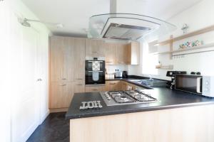 a kitchen with a black counter top and wooden cabinets at Homely 4BD Townhouse - Next to Hanley Park in Stoke on Trent