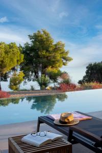 un cappello e dei bicchieri seduti su un tavolo accanto a una piscina di Theros Estate a Amfilochía