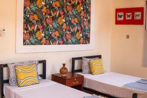 2 Betten in einem Zimmer mit Wandgemälde in der Unterkunft Tarawanda House by Stawi in Stone Town