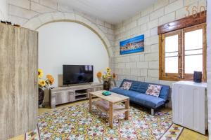 a living room with a blue couch and a tv at A lovely, 1BR home with lovely views in Isla BY 360 Estates in Senglea