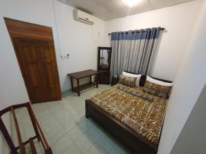 1 dormitorio con cama, mesa y puerta en Wilpattu homestay by Ceylon group, en Wilpattu