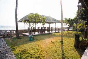 a pavilion on the beach next to the ocean at Temple Cafe & Cottages in Candidasa