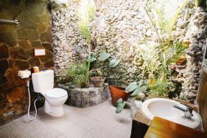 a bathroom with a toilet and a sink and plants at Temple Cafe & Cottages in Candidasa