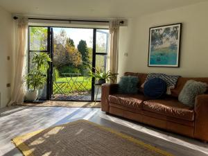 a living room with a brown couch and a large window at Halford House - Adults Only in Bourton on the Water