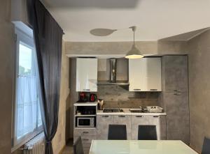 a kitchen with white cabinets and a large window at Basiglio Centro Storico in Basiglio