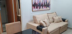 a couch with pillows sitting under a painting at Lindo apartamento no Litoral Norte in Camaçari