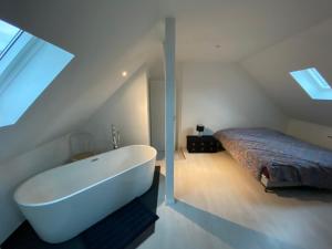 een wit bad in een kamer met een bed bij Superbe Duplex Strasbourg in Schiltigheim