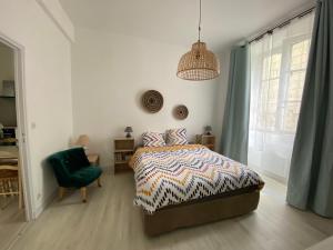 a bedroom with a bed and a green chair at Appartement Cosy avec vue sur le château in Chinon