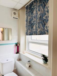 a bathroom with a toilet and a window at The Boho - 4 min walk to beach & town in Bournemouth