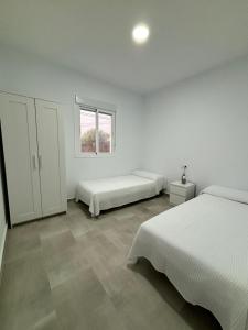 Habitación blanca con 2 camas y ventana en Mirador el atardecer en Cádiz