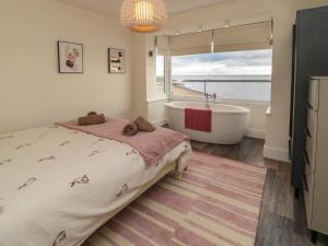a bedroom with a bed and a bath tub and a window at Fairwinds in Newbiggin-by-the-Sea