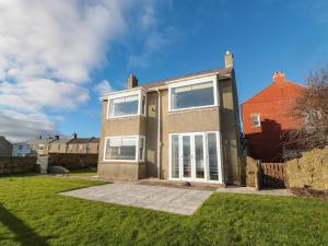 a brick house with large windows on a yard at Fairwinds in Newbiggin-by-the-Sea