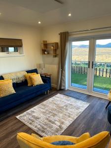 a living room with a blue couch and a large window at South Black Hill in Penicuik