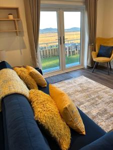 a blue couch with yellow pillows in a room with a window at South Black Hill in Penicuik