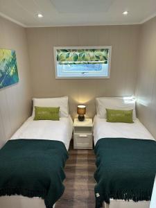 2 camas en una habitación pequeña con almohadas verdes en South Black Hill, en Penicuik