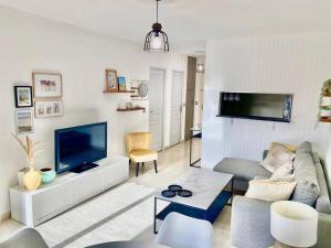 a living room with a couch and a tv at Le Central Spacieux avec loggia in Saint-Raphaël
