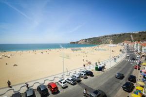 Una playa con muchos coches estacionados junto a una playa en Holidays Nazaré marginal, en Nazaré