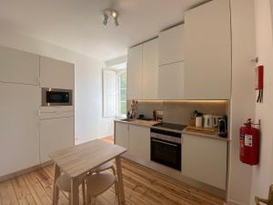 a kitchen with white cabinets and a wooden table at Sintra Clássica in Sintra