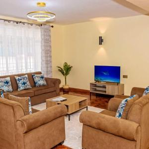 a living room with couches and a flat screen tv at Taliah Homestays in Nanyuki