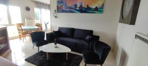 sala de estar con sofá negro y mesa en les pieds dans l'eau à 50 mètres de la mer, en Saint-Quay-Portrieux
