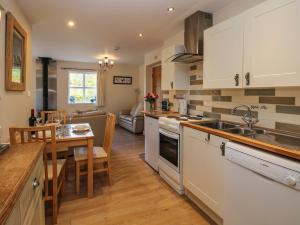 a kitchen with white cabinets and a table and a dining room at Alyn View in Llanferres