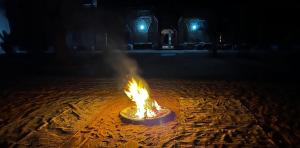 a fire in the middle of a street at night at Hotel Camping Les Roses Des Dunes in Merzouga