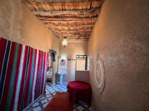 una camera con un tavolo rosso in una stanza con soffitto di Hotel Camping Les Roses Des Dunes a Merzouga