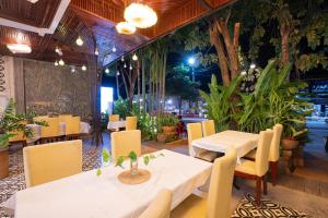 a restaurant with white tables and chairs and plants at Victoria Central Residence in Siem Reap