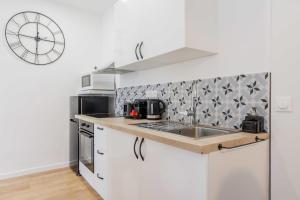 uma cozinha com um lavatório e um relógio na parede em Charming Apartment 6Pax in Vibrant Rue d'Hauteville em Paris