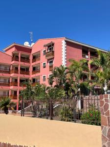 a pink building with palm trees in front of it at Vivienda del Sol in Palm-Mar