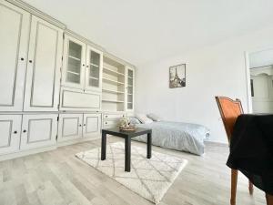 Dormitorio blanco con cama y mesa en Appartement 2 pièces proche Enghien-Les-Bains, en Soisy-sous-Montmorency
