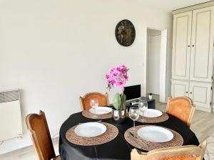 een eetkamer met een tafel met borden en stoelen bij Appartement 2 pièces proche Enghien-Les-Bains in Soisy-sous-Montmorency