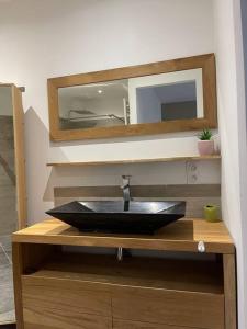 een badkamer met een zwarte wastafel en een spiegel bij Un cocon au cœur du village in Saintes-Maries-de-la-Mer