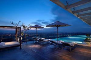 un patio con mesas, sombrillas y una piscina en JW Marriott Hotel Medan en Medan