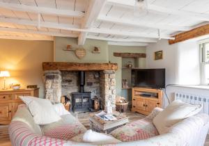 a living room with a couch and a stone fireplace at Ivy Cottage in Low Eskcleth