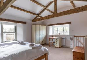 a bedroom with a bed and a desk and windows at Ivy Cottage in Low Eskcleth