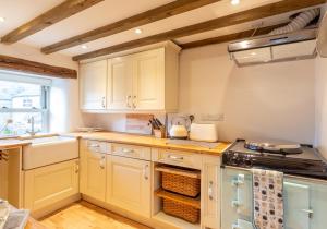 a kitchen with white cabinets and a stove top oven at Ivy Cottage in Low Eskcleth